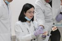 One female student and two faculty members practicing on a model of teeth